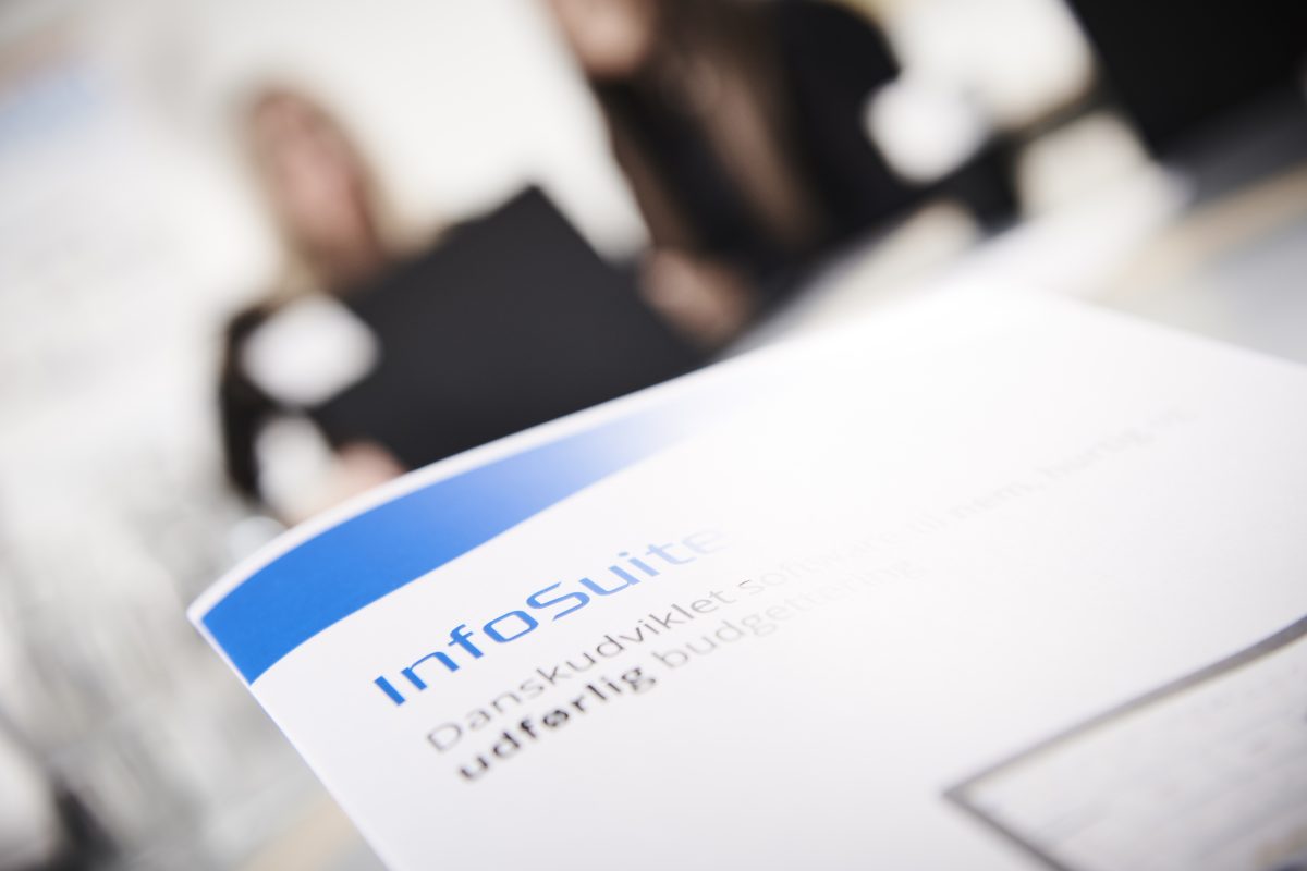 Et billede af en InfoSuite-brochure med to medarbejdere i baggrunden. 